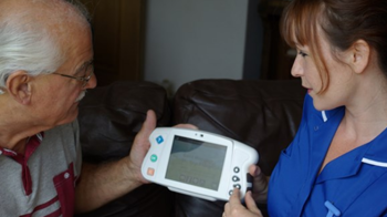 A nurse speaking to an older man They are both looking at an electronic tablet